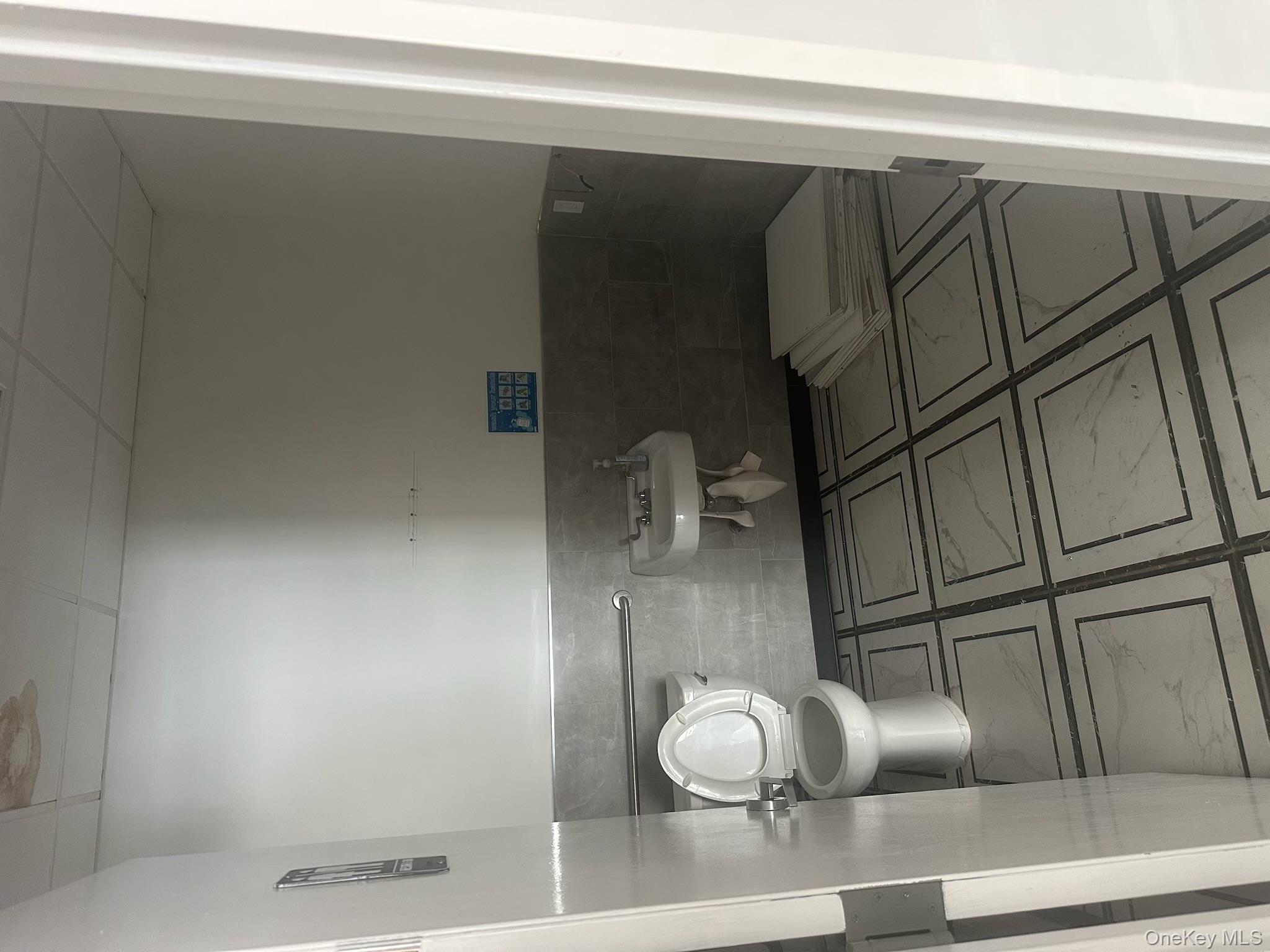 Half bathroom featuring tile walls, a wainscoted wall, and a drop ceiling