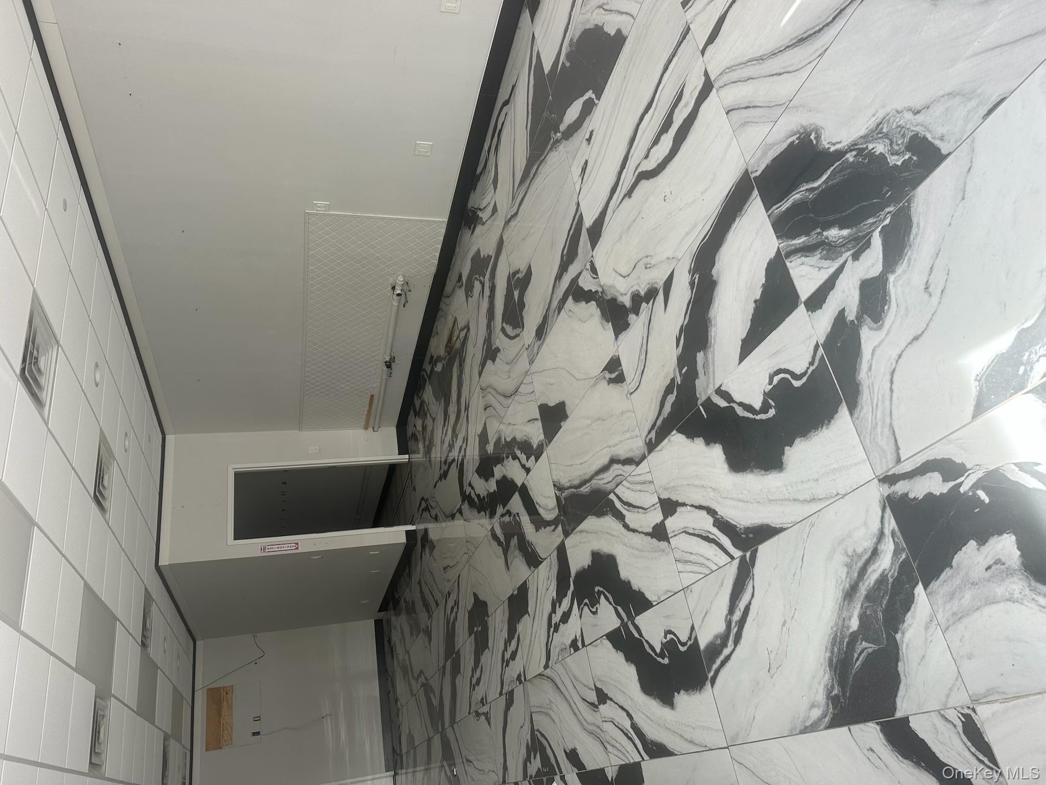 Unfurnished room featuring a drop ceiling and light marble finish flooring