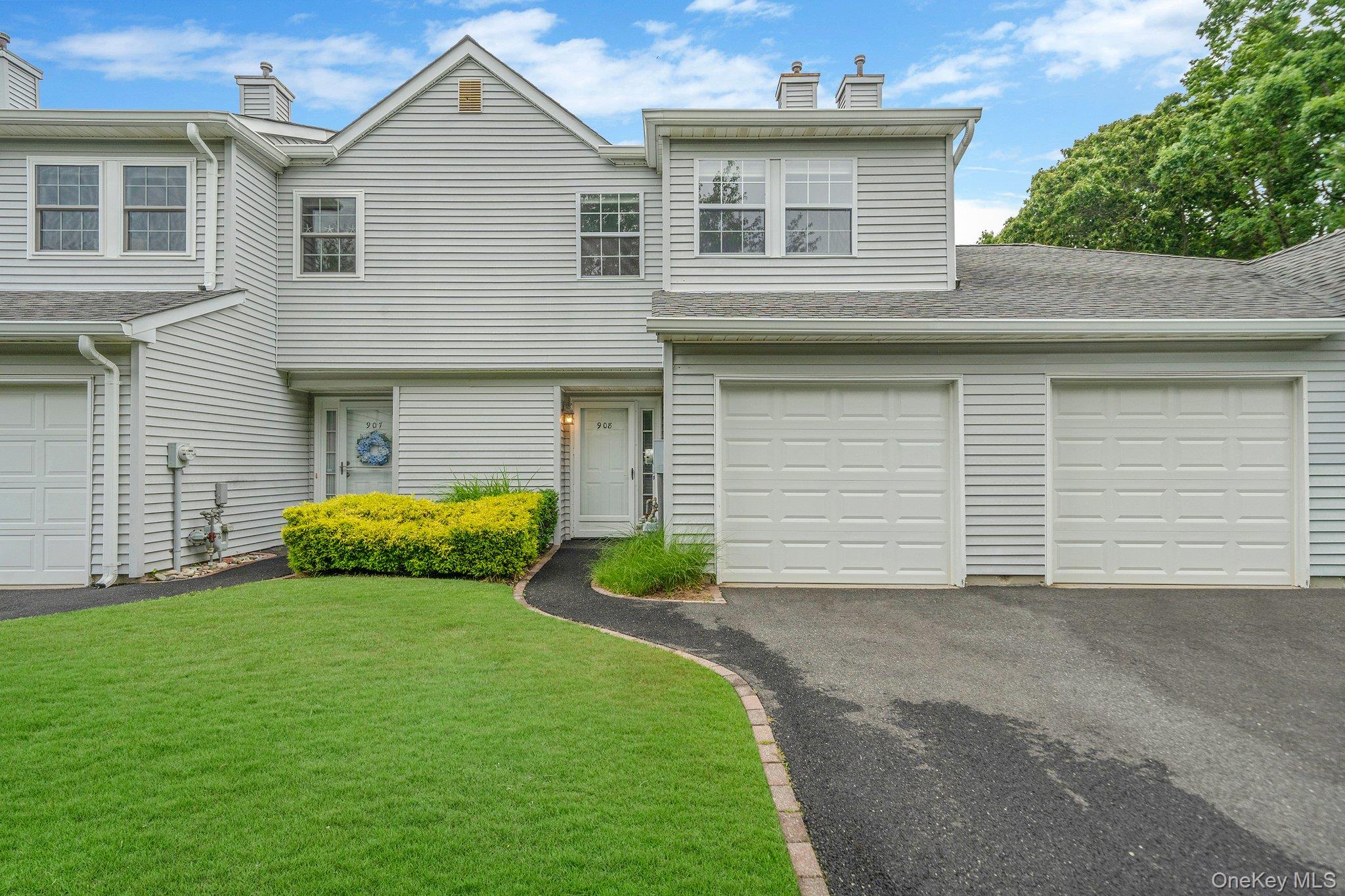 Traditional-style house featuring a chimney, driveway, a garage, and a front lawn