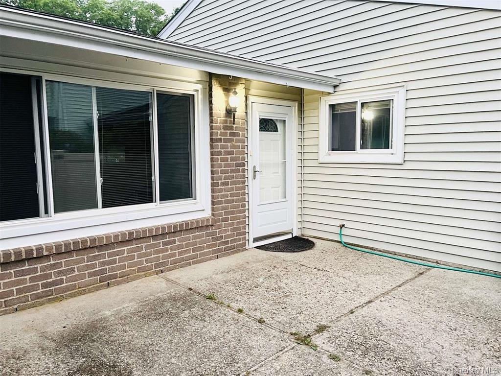 Property entrance with brick siding and a patio