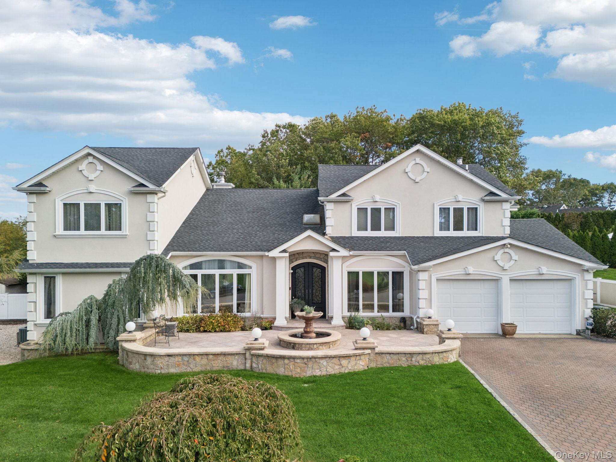 Traditional-style house with roof with shingles, stucco siding, and a front yard