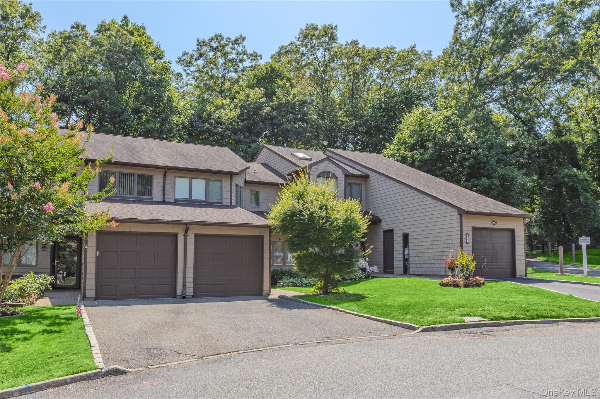 View of front of house featuring a front yard, roof with shingles, a garage, and driveway