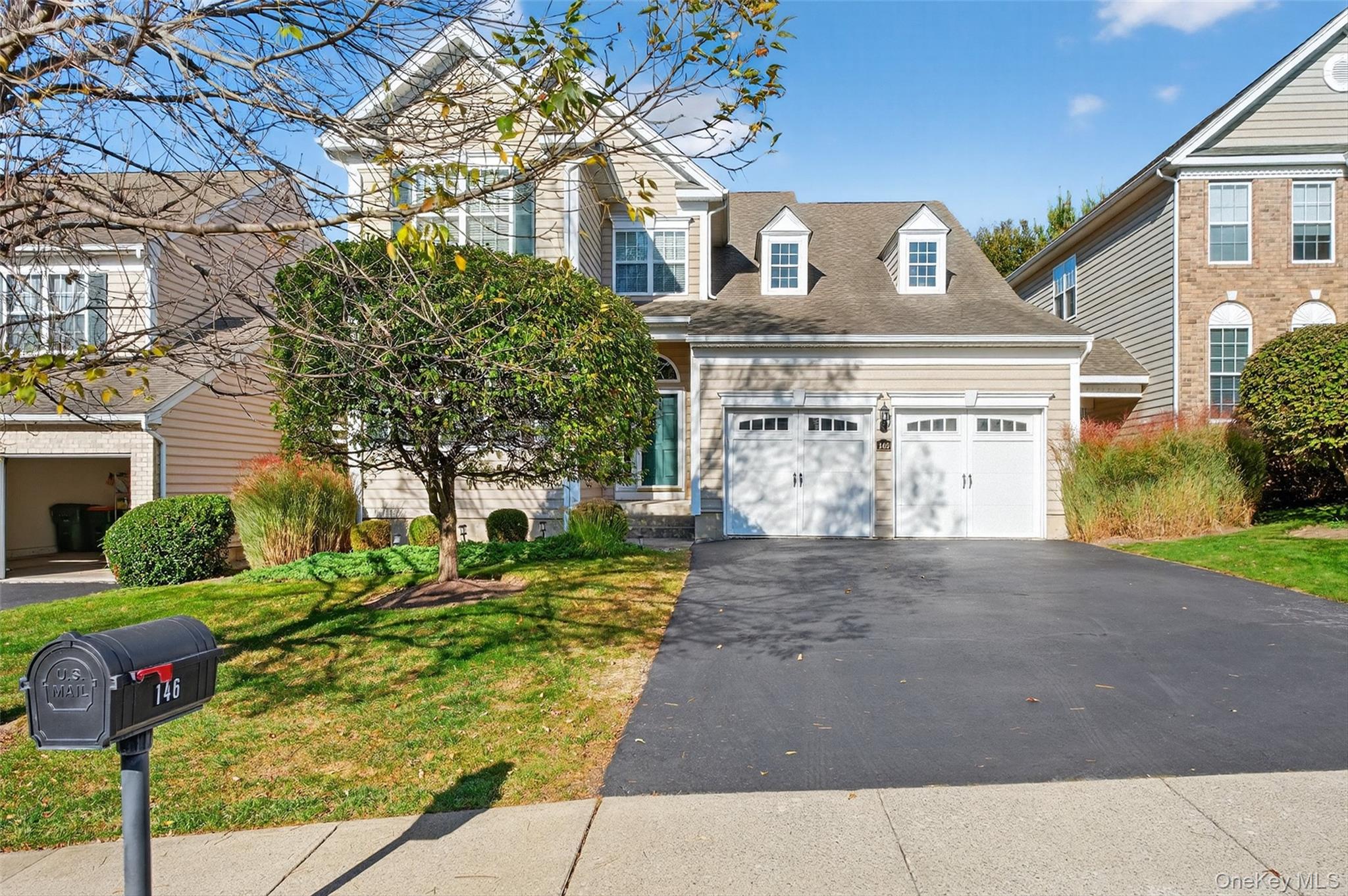 Traditional home with asphalt driveway, a front lawn, and an attached garage