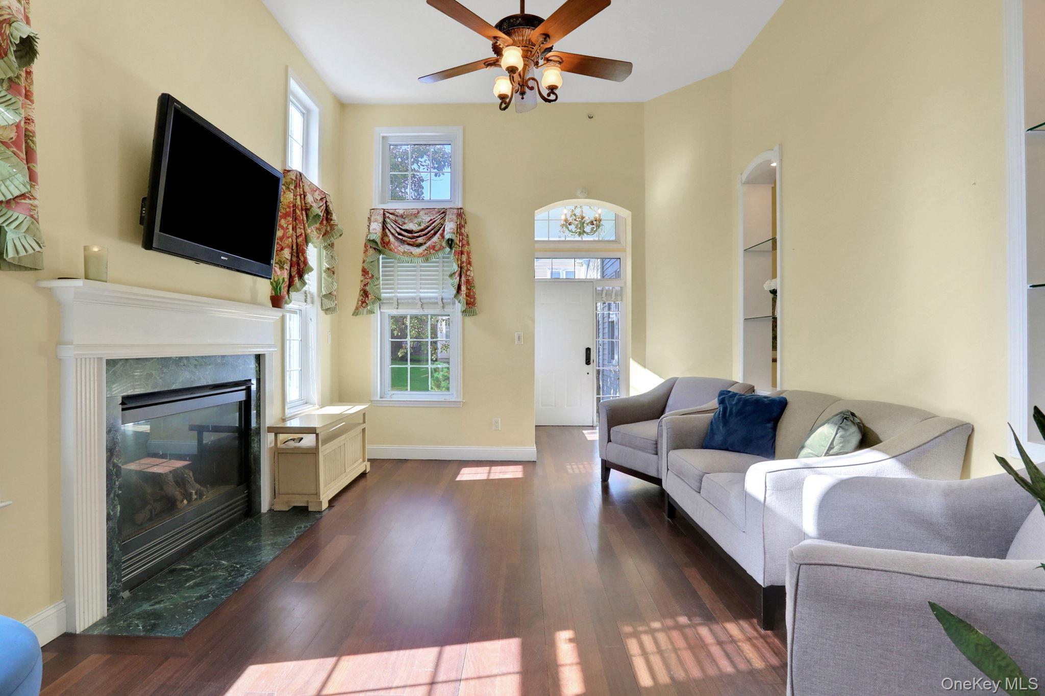 Living room featuring dark wood-style flooring, a ceiling fan, and a premium fireplace