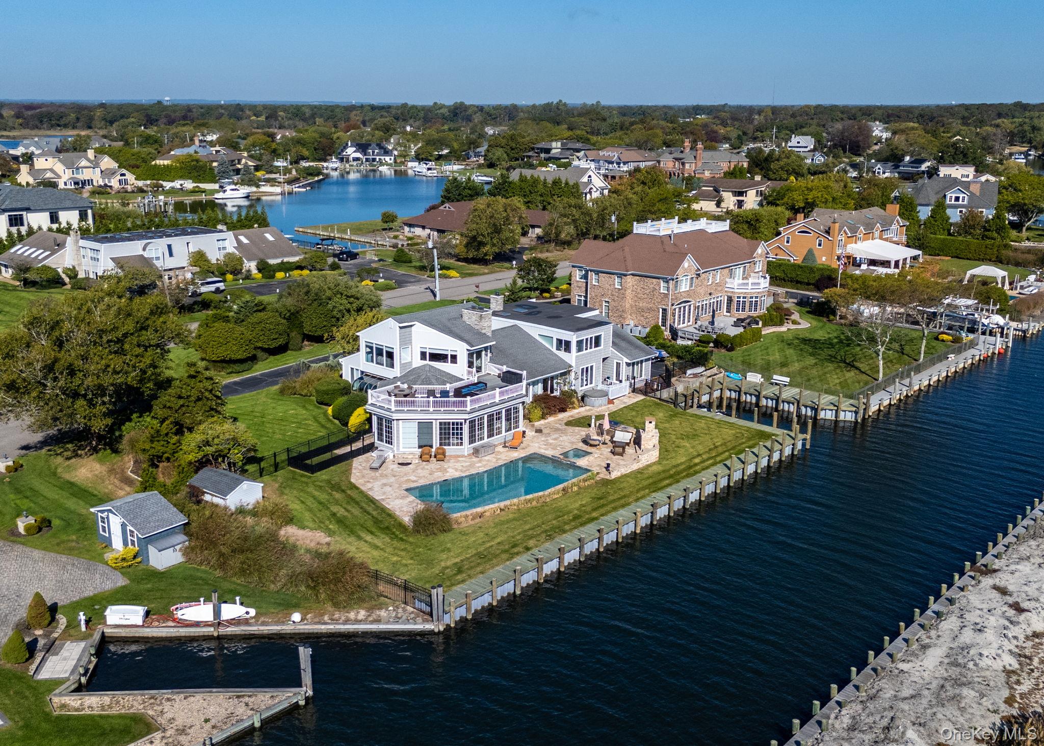 Aerial view of residential area featuring a nearby body of water and a pool