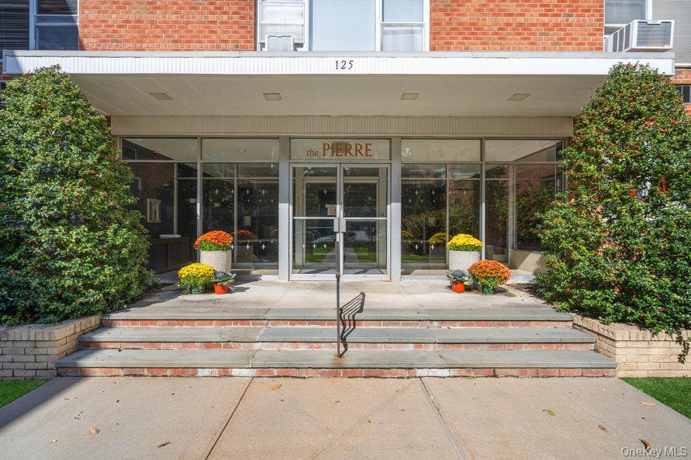 View of exterior entry with brick siding and a sunroom