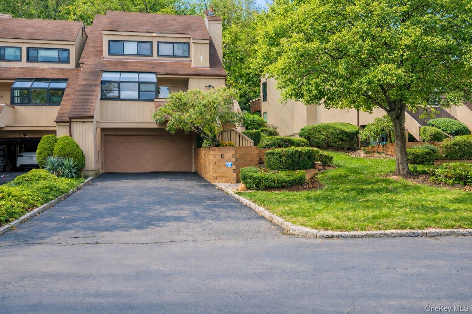 View of front of house with asphalt driveway, a chimney, a garage, and a shingled roof