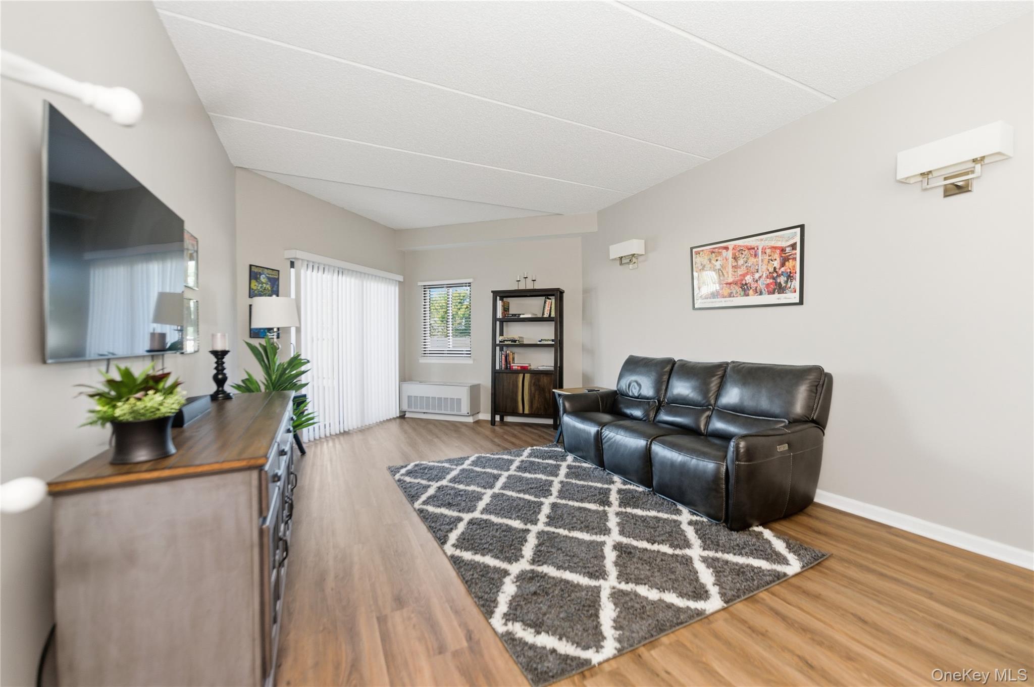 Living area with light wood-style flooring and radiator heating unit