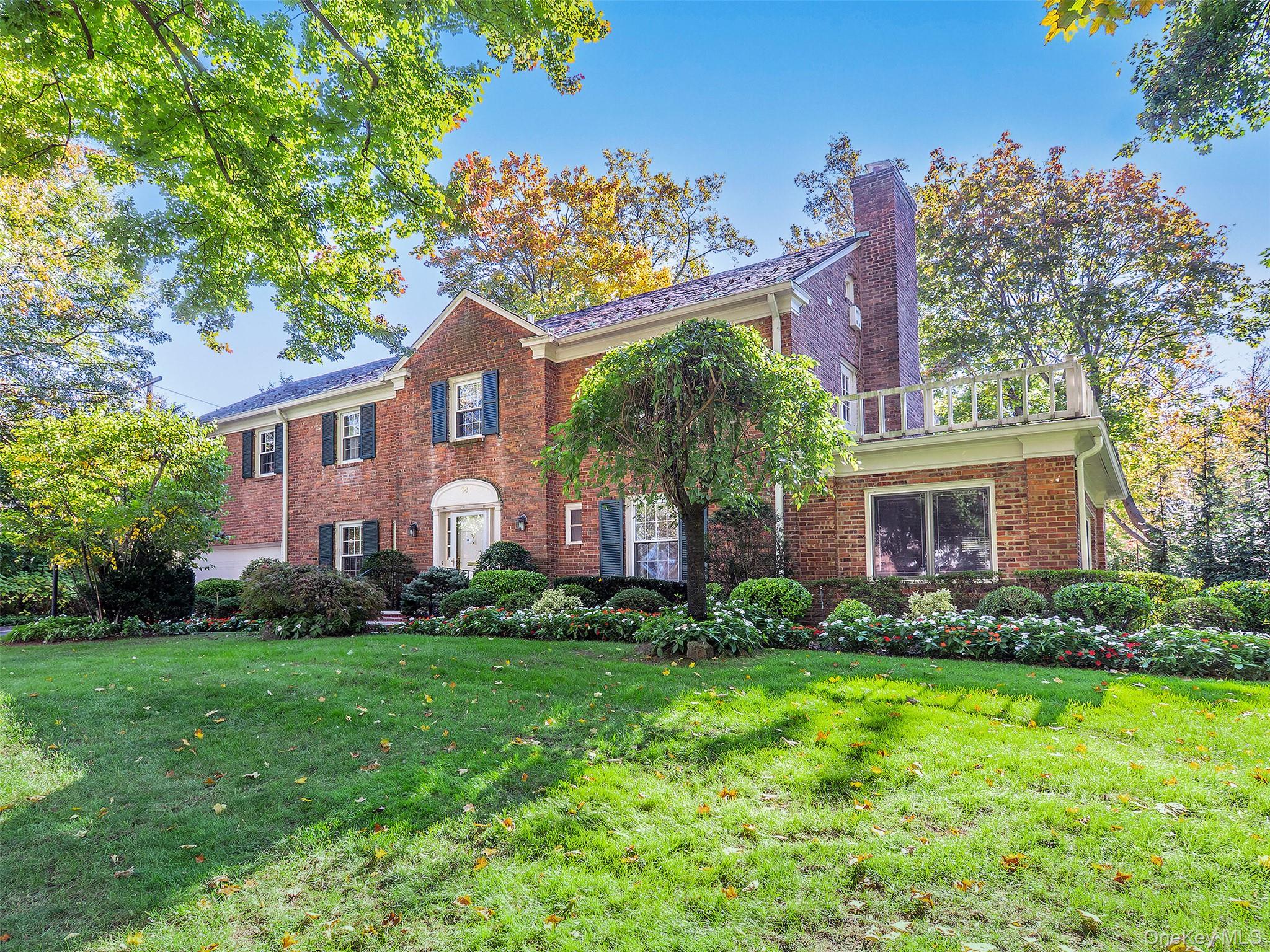 View of front of house featuring a front yard, a chimney, and brick siding