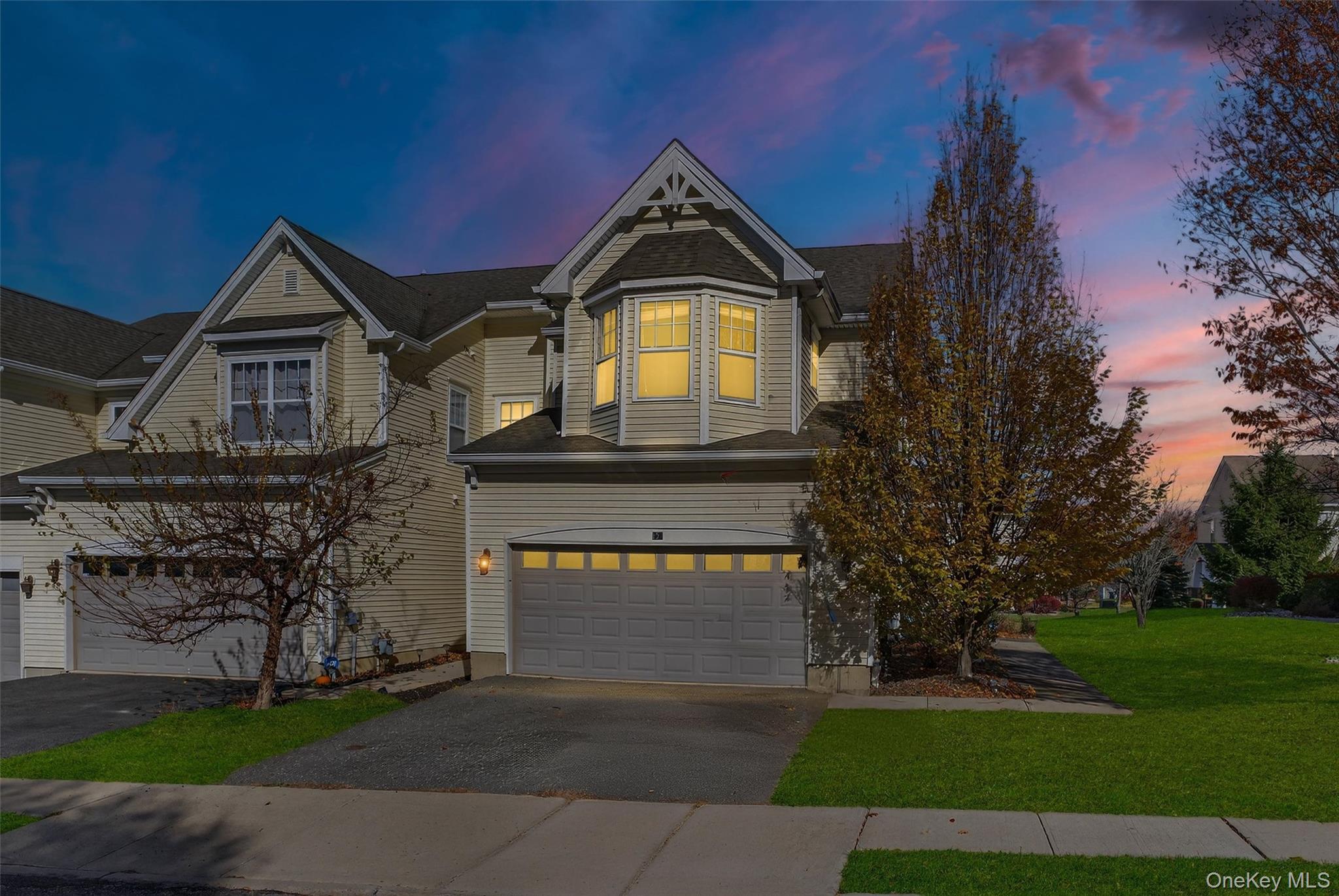 View of front of home with driveway, a garage, and a lawn