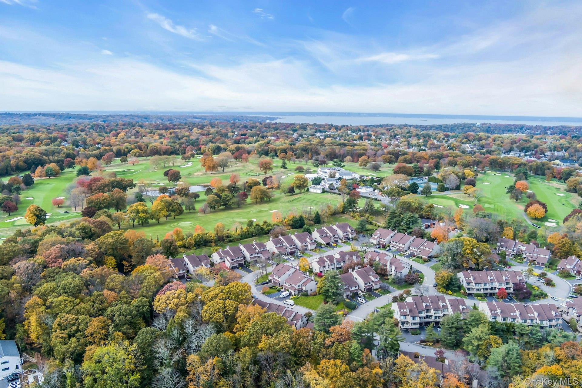 Aerial view of residential area with a golf course and a nearby body of water
