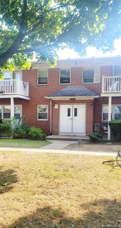 Traditional-style house with a balcony, brick siding, and a front yard