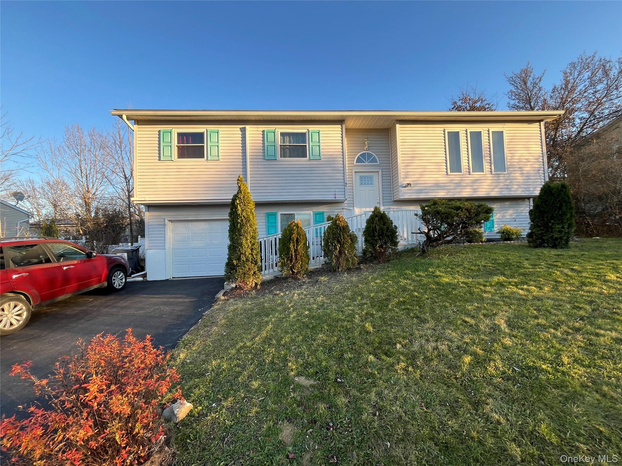 Split foyer home with asphalt driveway, an attached garage, and a front lawn