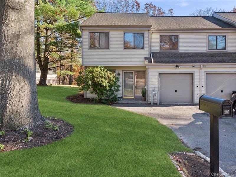 View of front of house with roof with shingles, a front yard, asphalt driveway, and a garage
