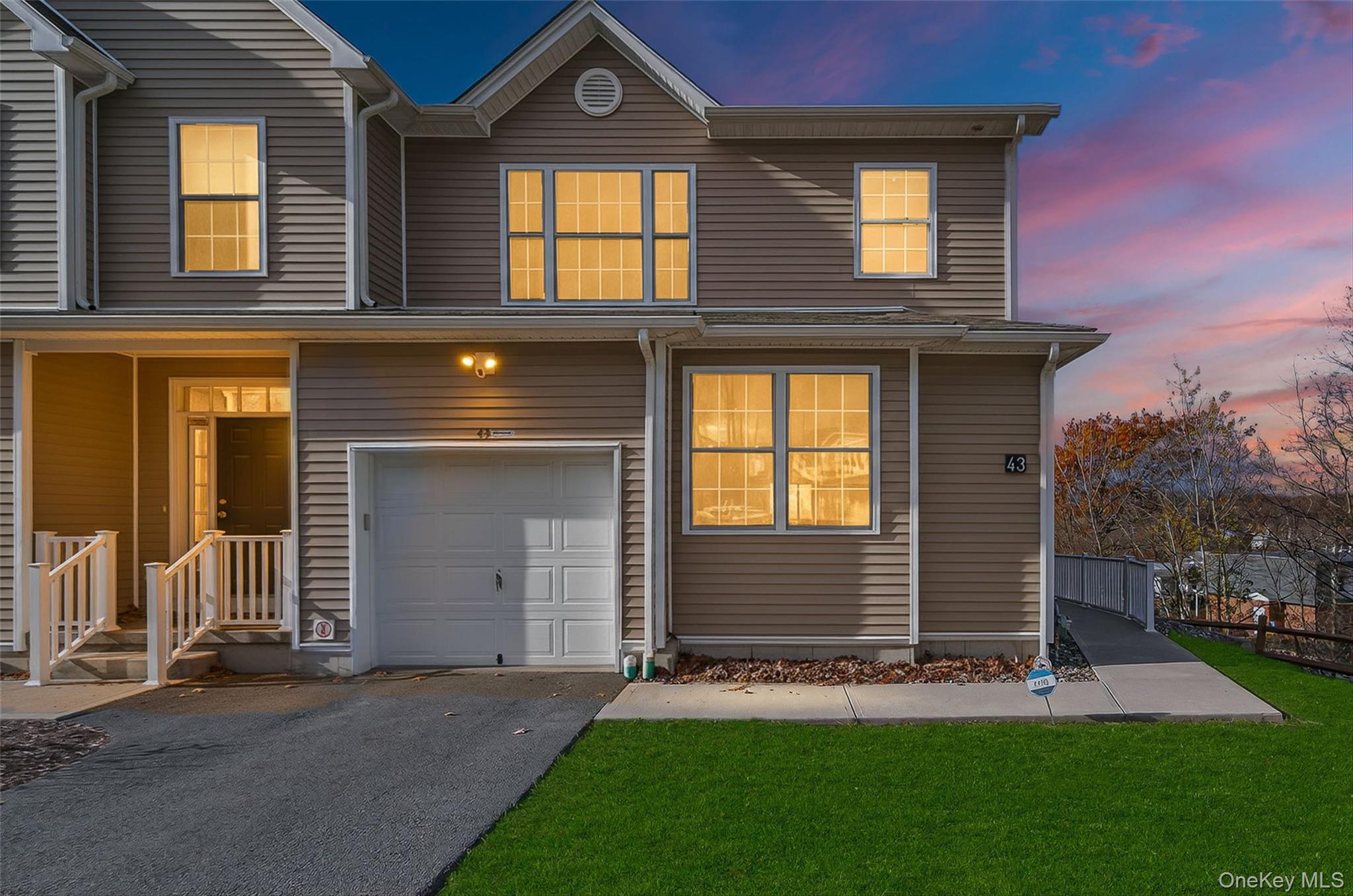 Traditional-style house with an attached garage, driveway, and a front yard