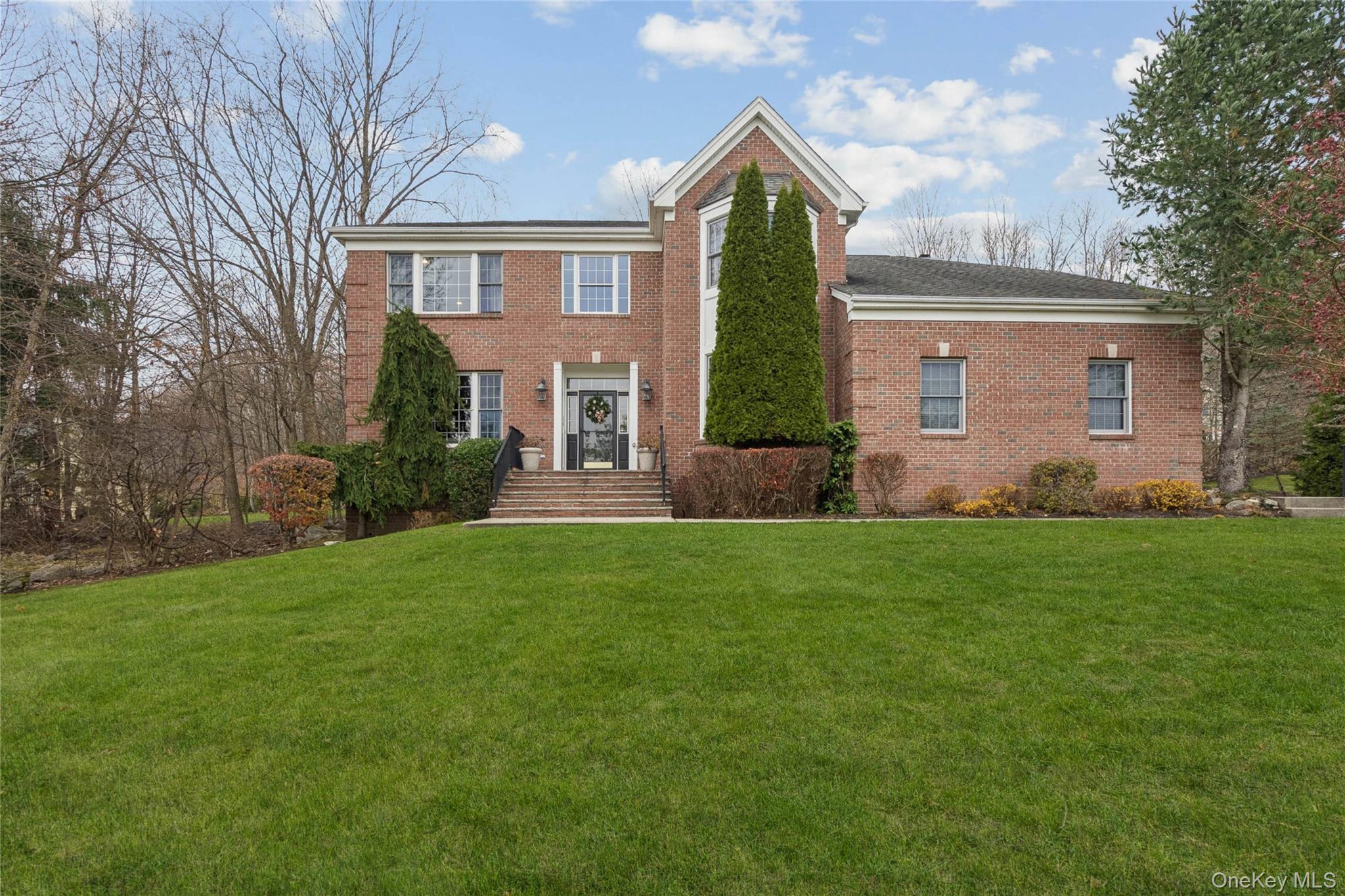 Colonial-style house featuring a front lawn and brick siding