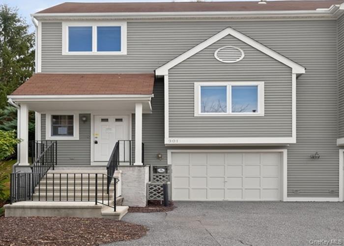 View of front of property with a porch, driveway, and an attached garage