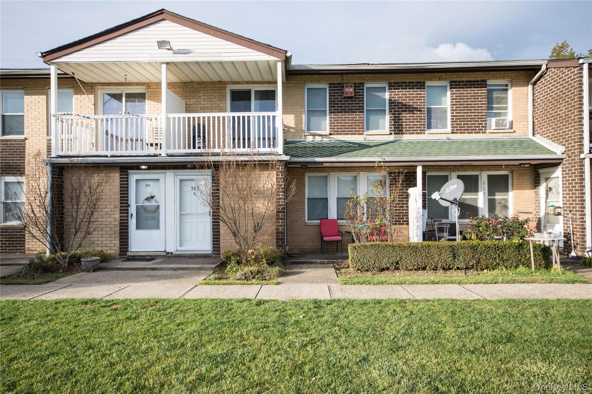 Traditional-style house featuring a balcony, a front lawn, and brick siding