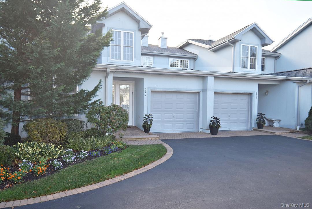 Traditional-style house featuring asphalt driveway, stucco siding, and a garage