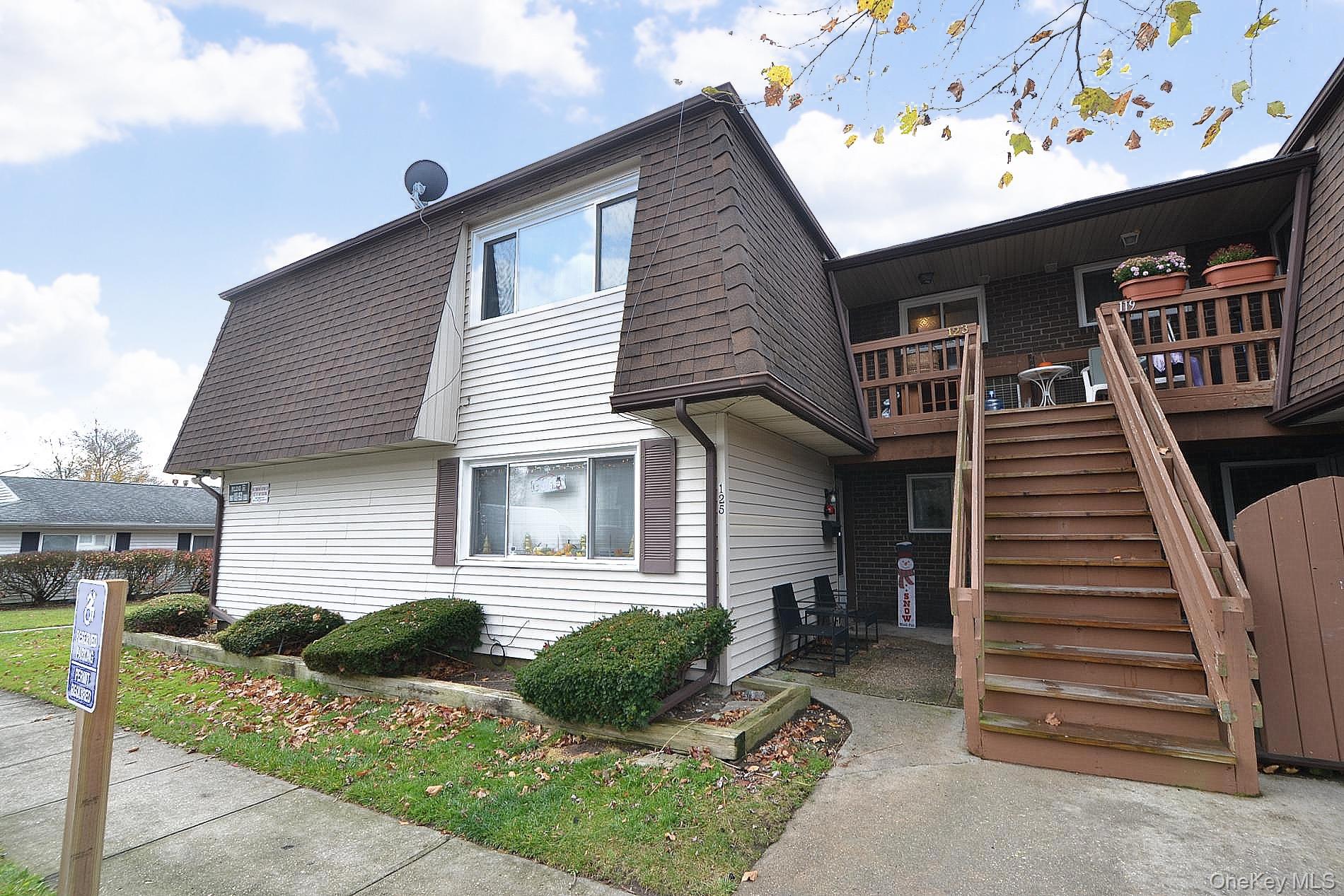 View of side of property featuring stairway and roof with shingles