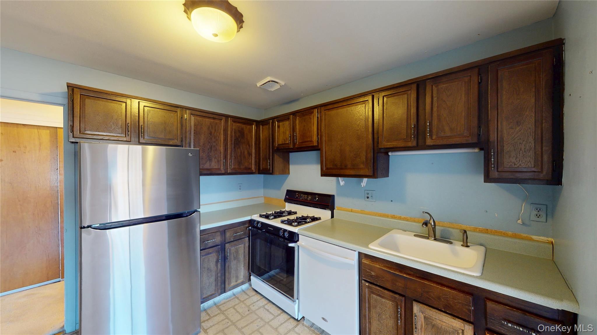 Kitchen with white appliances, light countertops, and brick patterned flooring