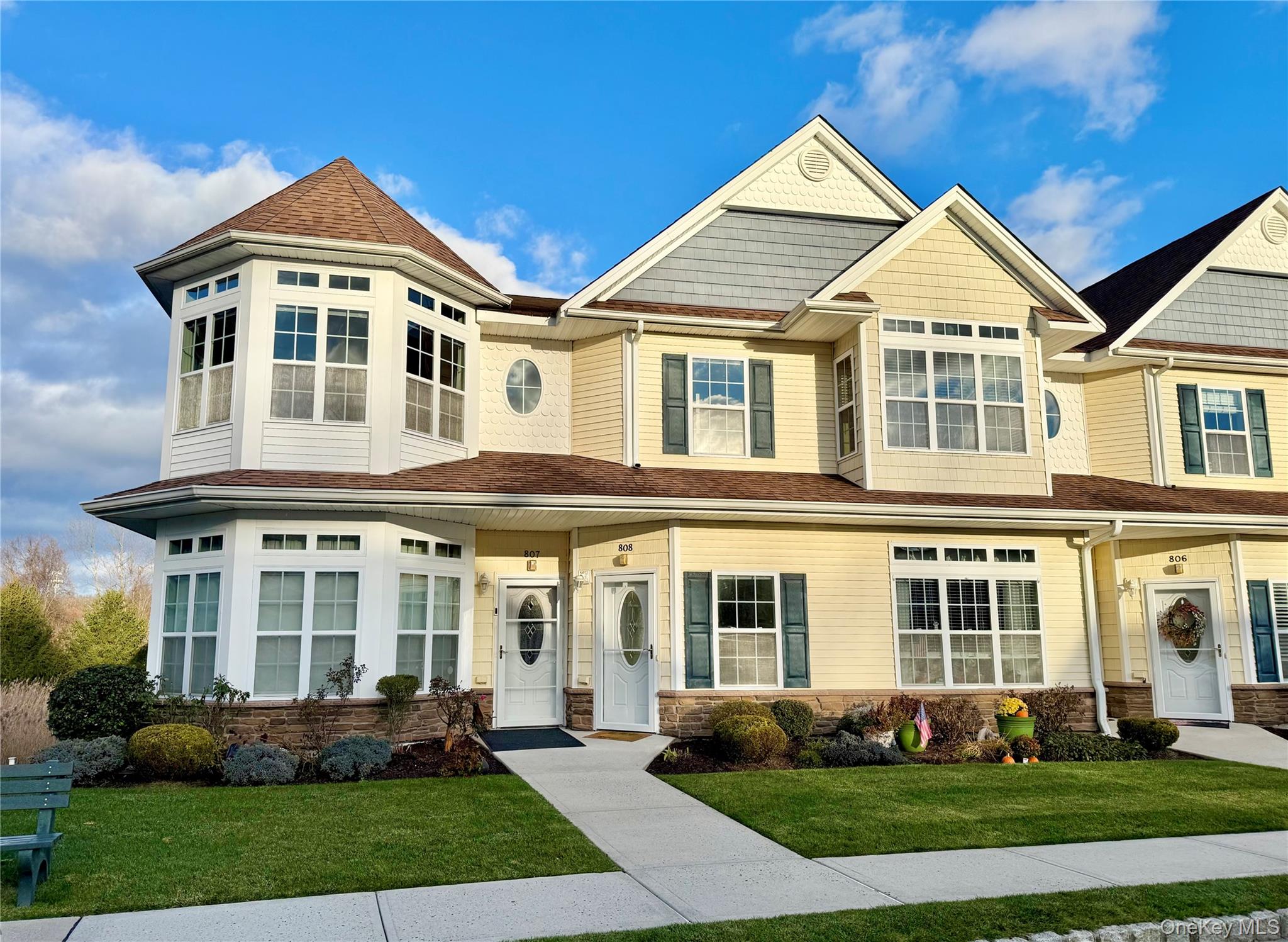 View of front of home with a front yard, stone siding, and a shingled roof