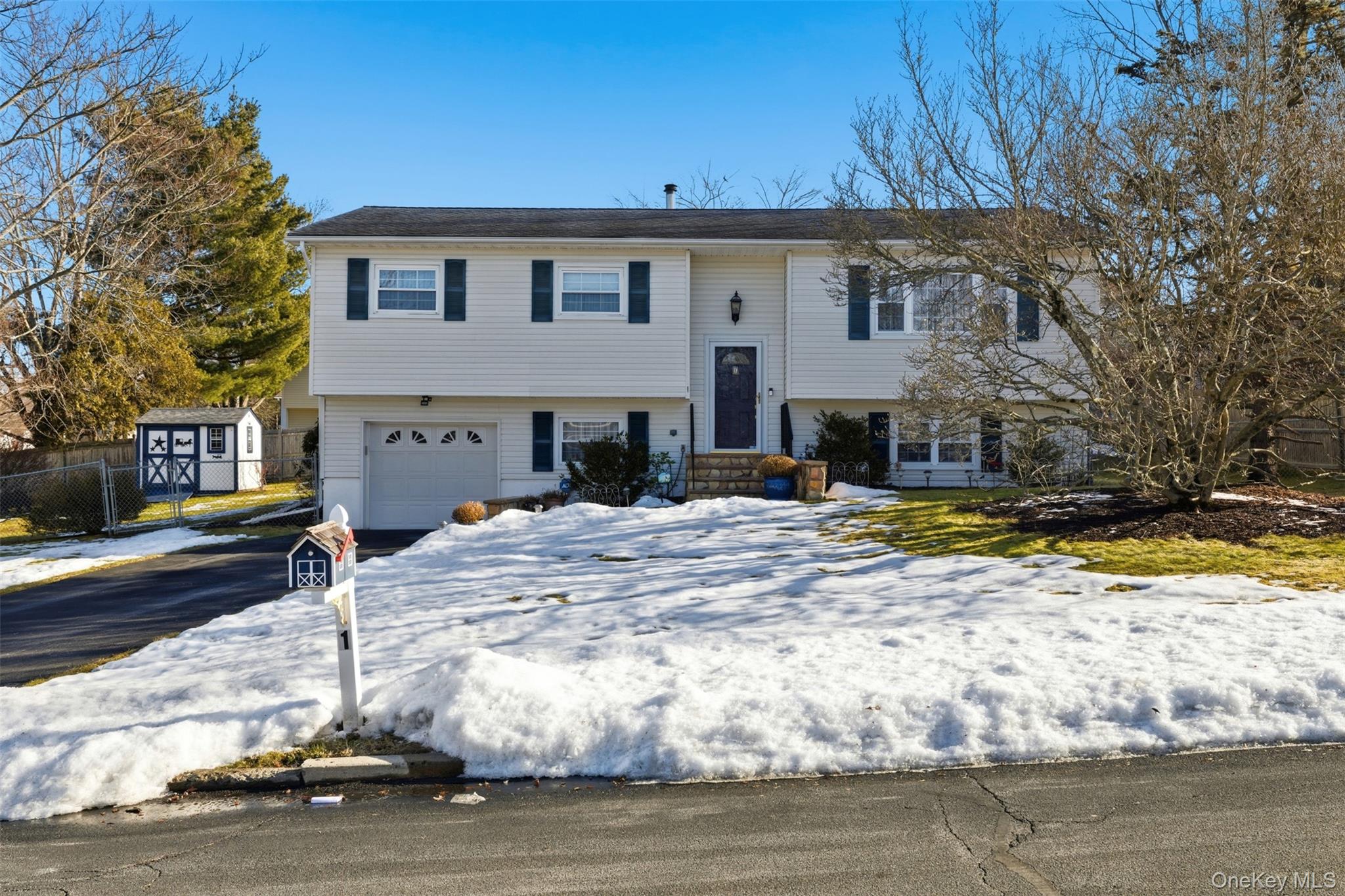 Bi-level home featuring a garage and asphalt driveway