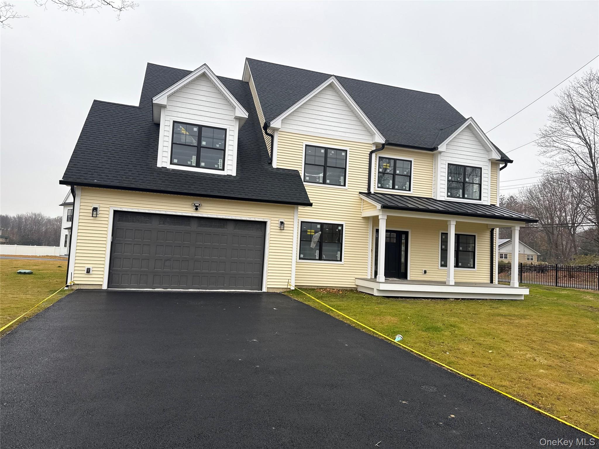 Modern farmhouse featuring driveway, a porch, a front lawn, an attached garage, and a shingled roof