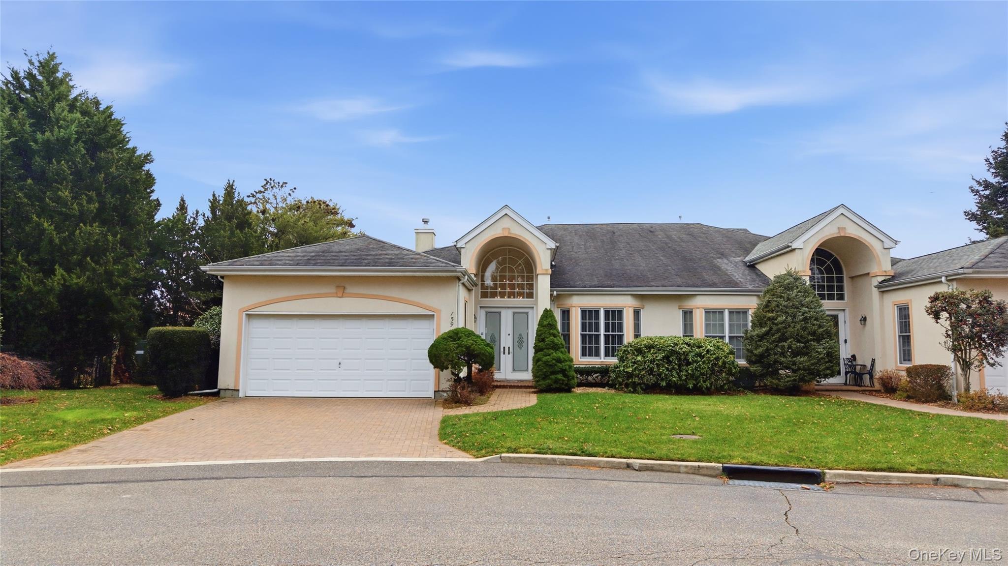 View of front facade with stucco siding, a front yard, driveway and two car garage