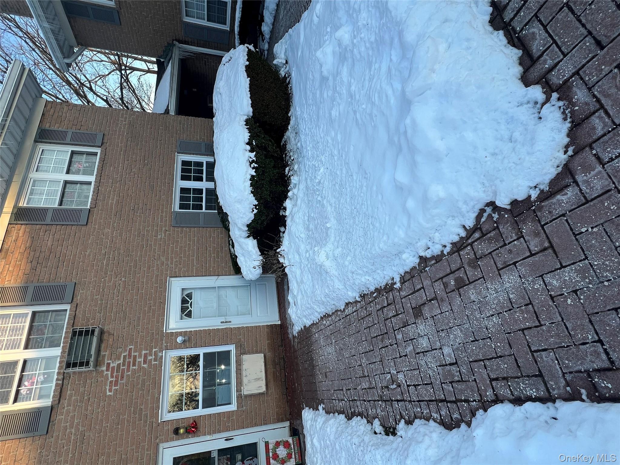 Snow covered property entrance with brick siding