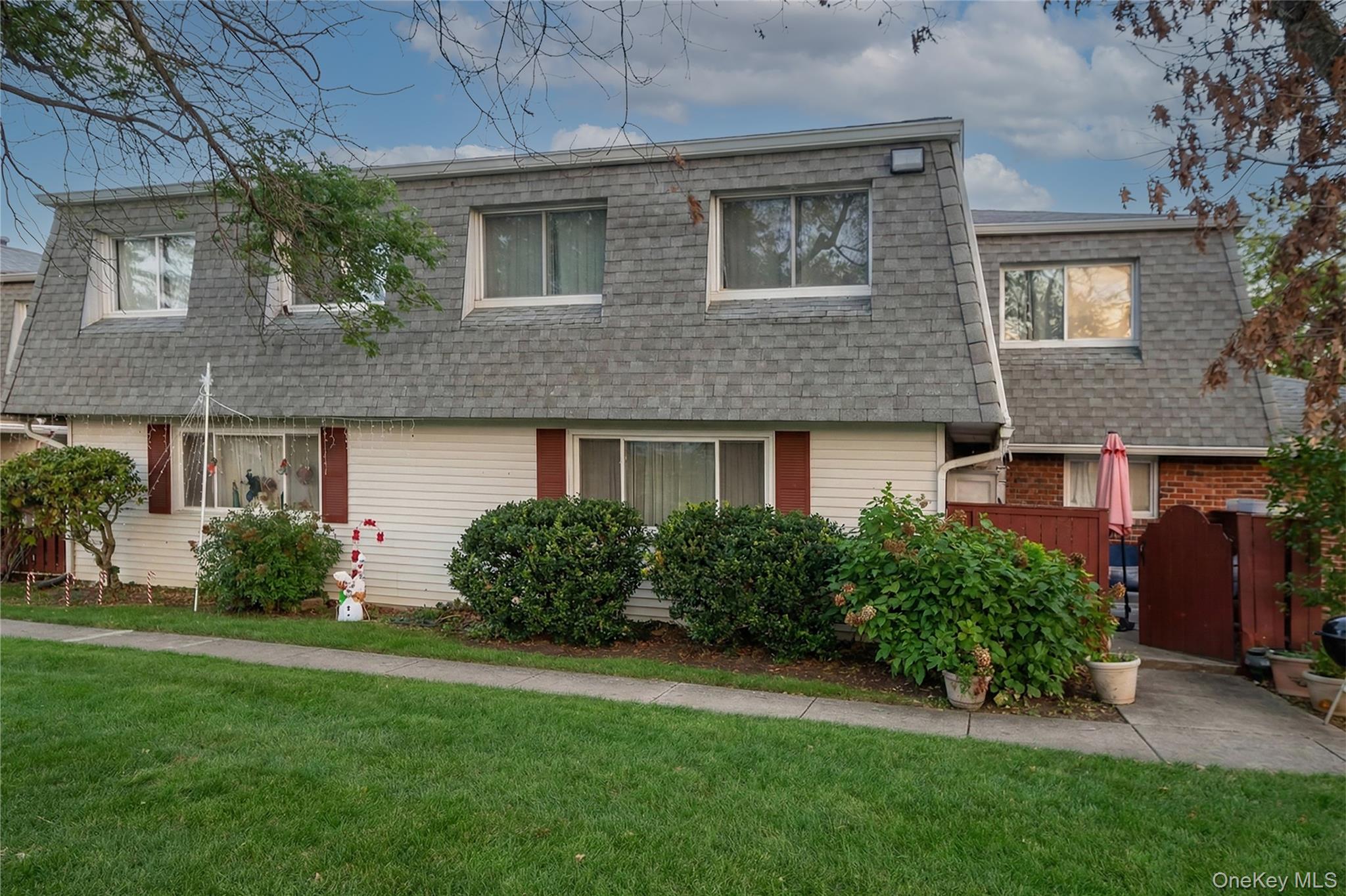 Front of property featuring mansard roof, a shingled roof, and brick siding