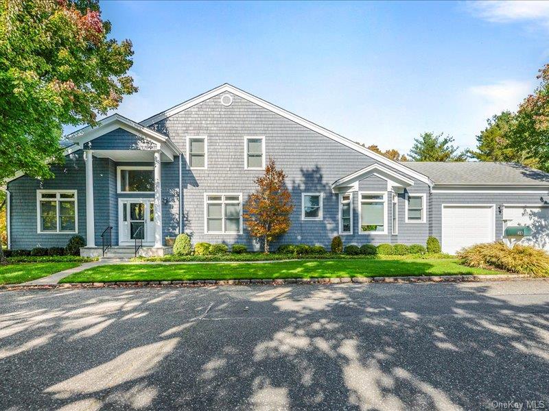 Shingle-style home featuring a front lawn and a garage