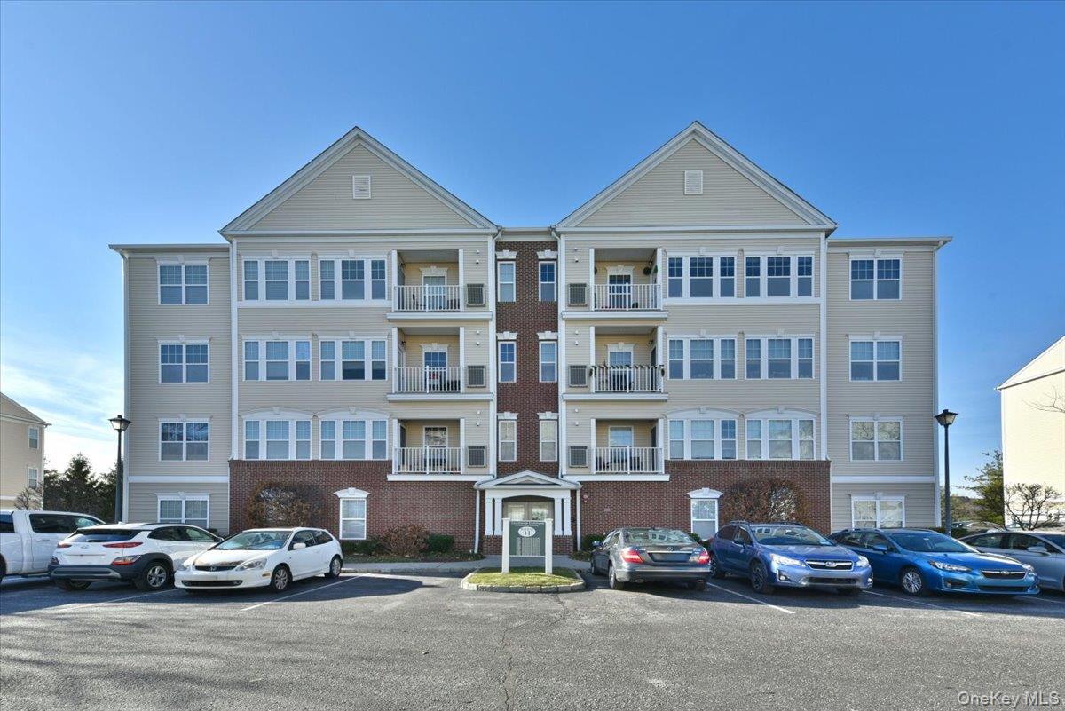 View of apartment building / complex with uncovered parking