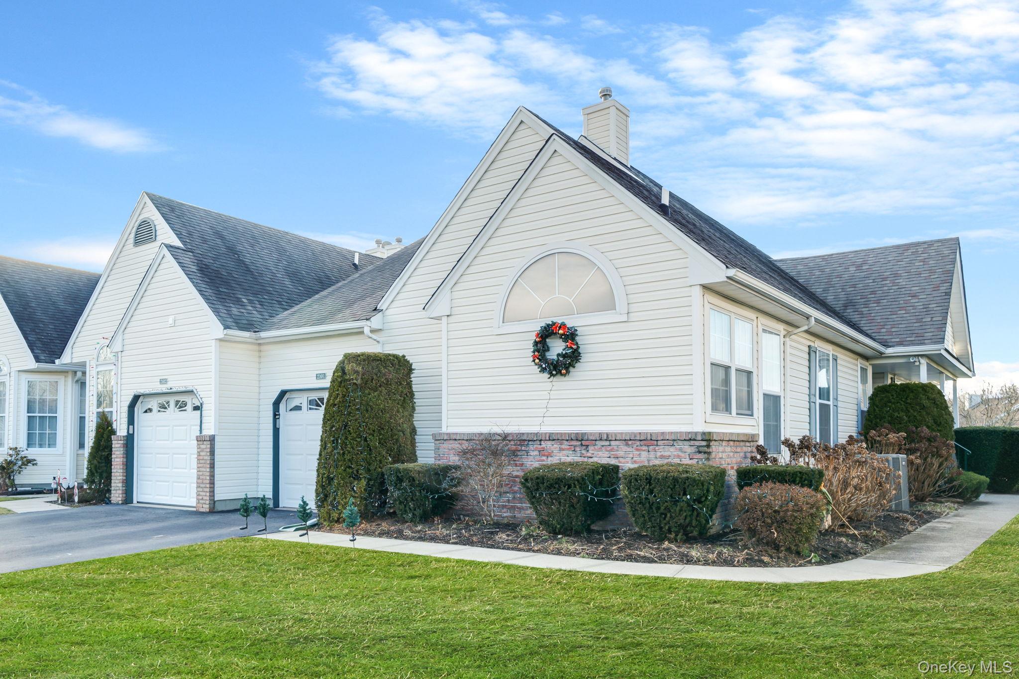 View of side of property with a yard, asphalt driveway, a shingled roof, a chimney, and brick siding