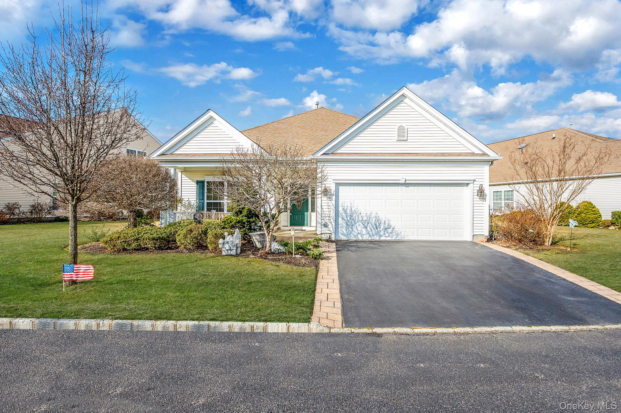 Single story home featuring asphalt driveway, a front lawn, covered porch, an attached garage, and a shingled roof