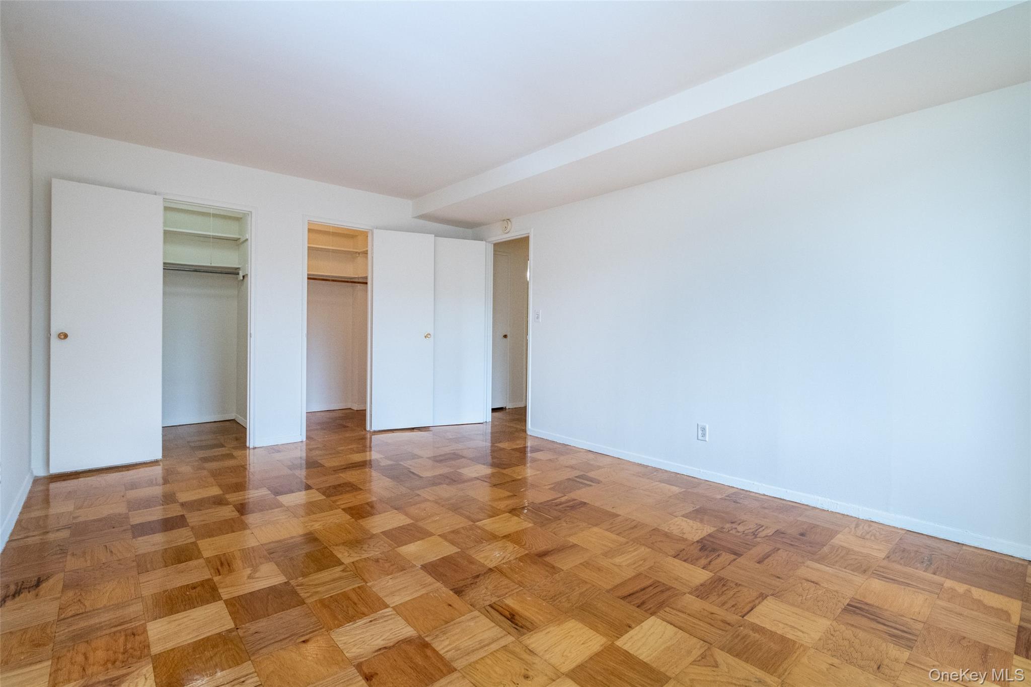 Unfurnished bedroom featuring multiple closets and baseboards