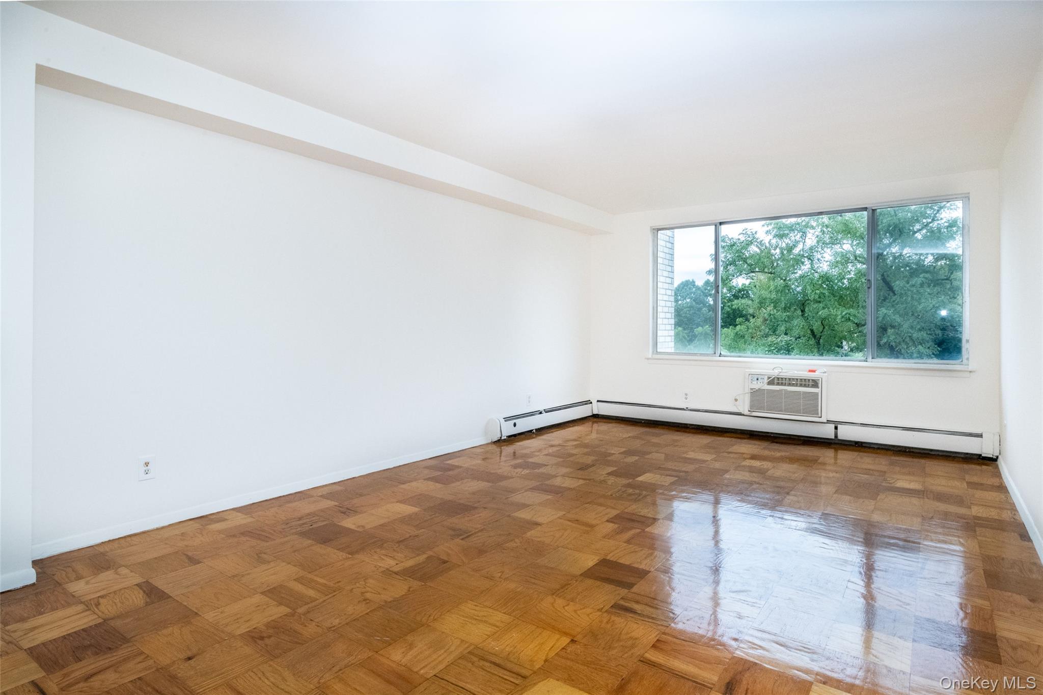 Empty room featuring baseboard heating and a wall mounted air conditioner