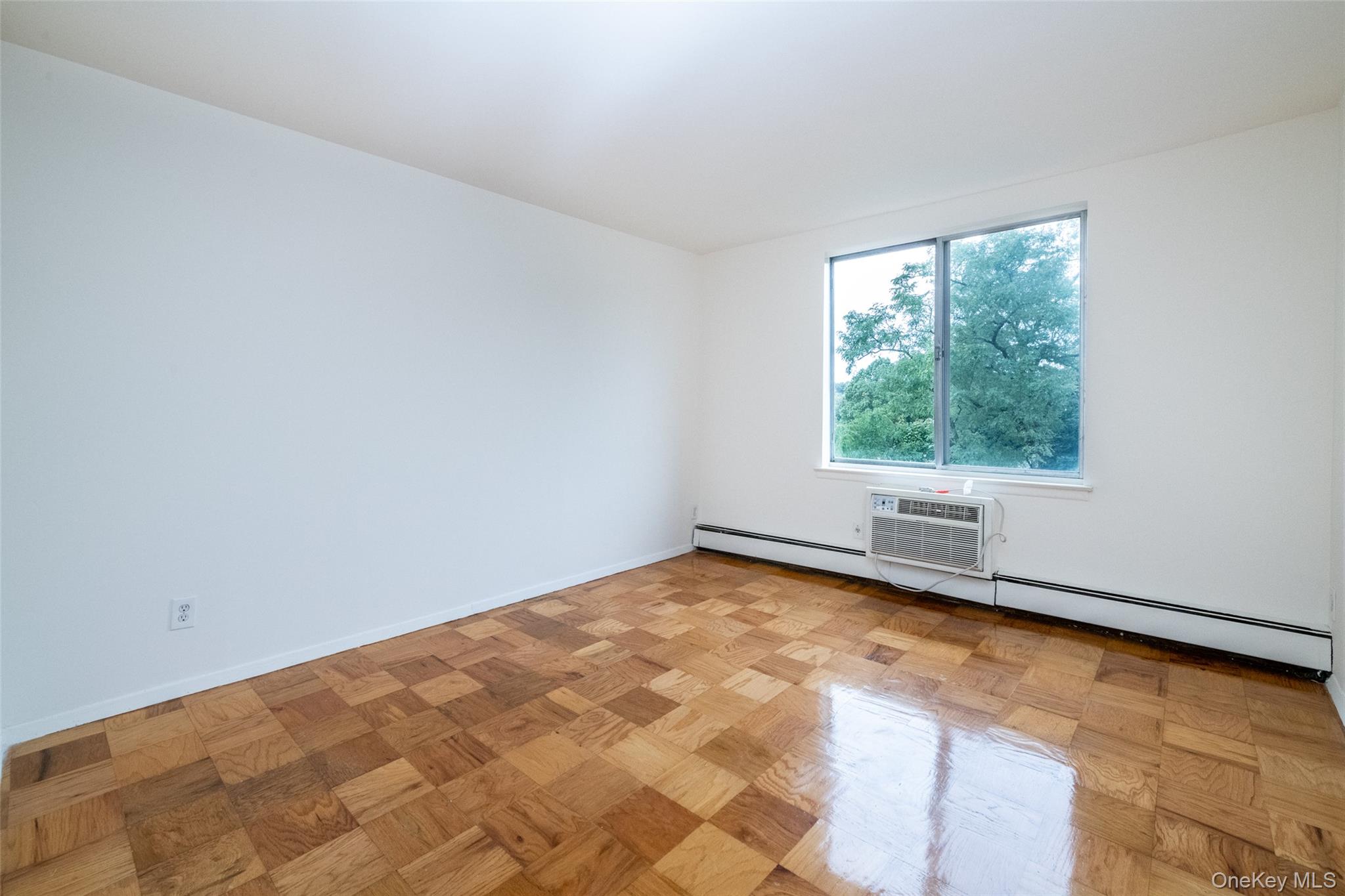 Spare room with a baseboard heating unit and a wall unit AC