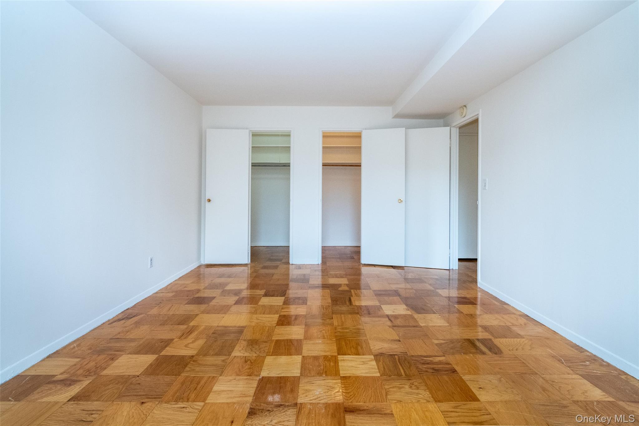Unfurnished bedroom featuring two closets and baseboards