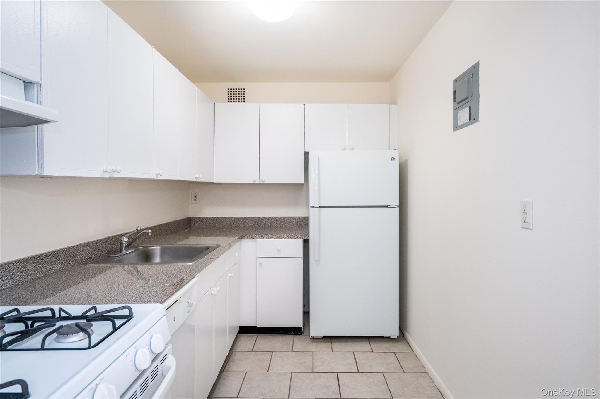 Kitchen featuring white appliances, white cabinetry, and light tile patterned flooring
