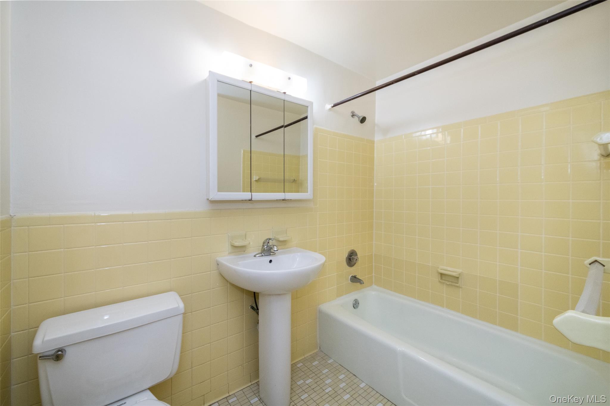 Full bath featuring shower / bathtub combination, wainscoting, tile walls, and tile patterned flooring
