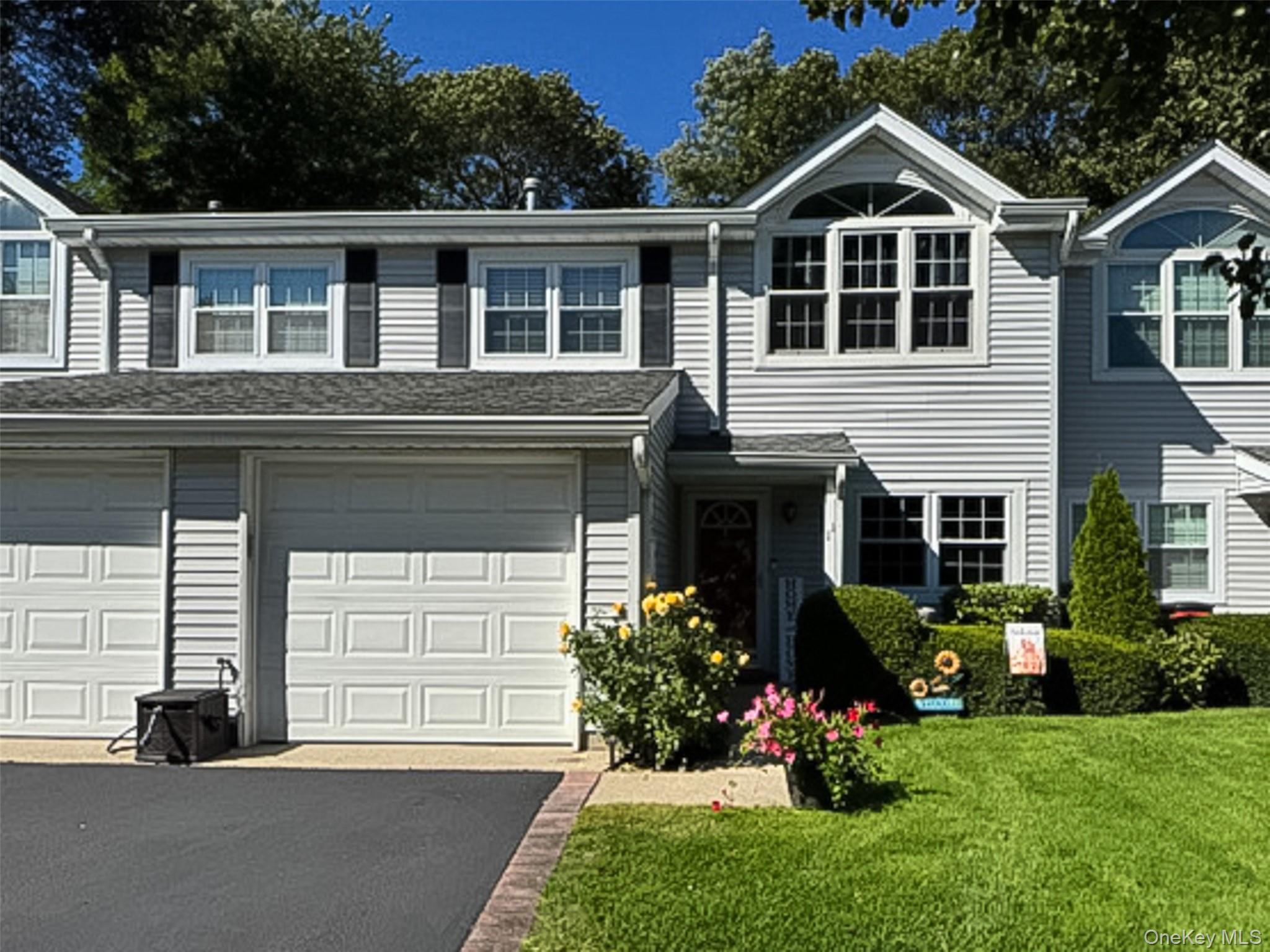 Traditional-style house with asphalt driveway, a front lawn, and an attached garage