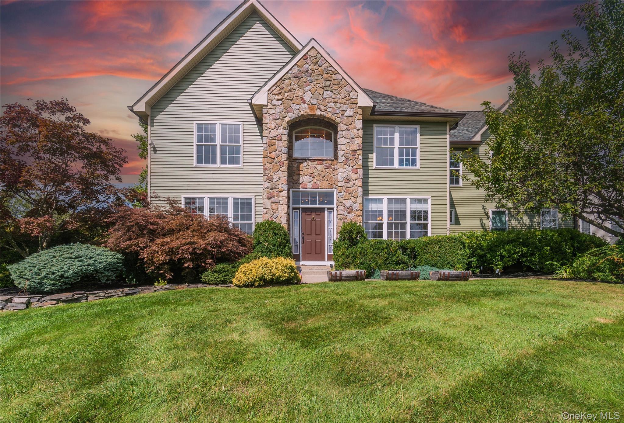 Traditional-style home featuring stone siding and a lawn