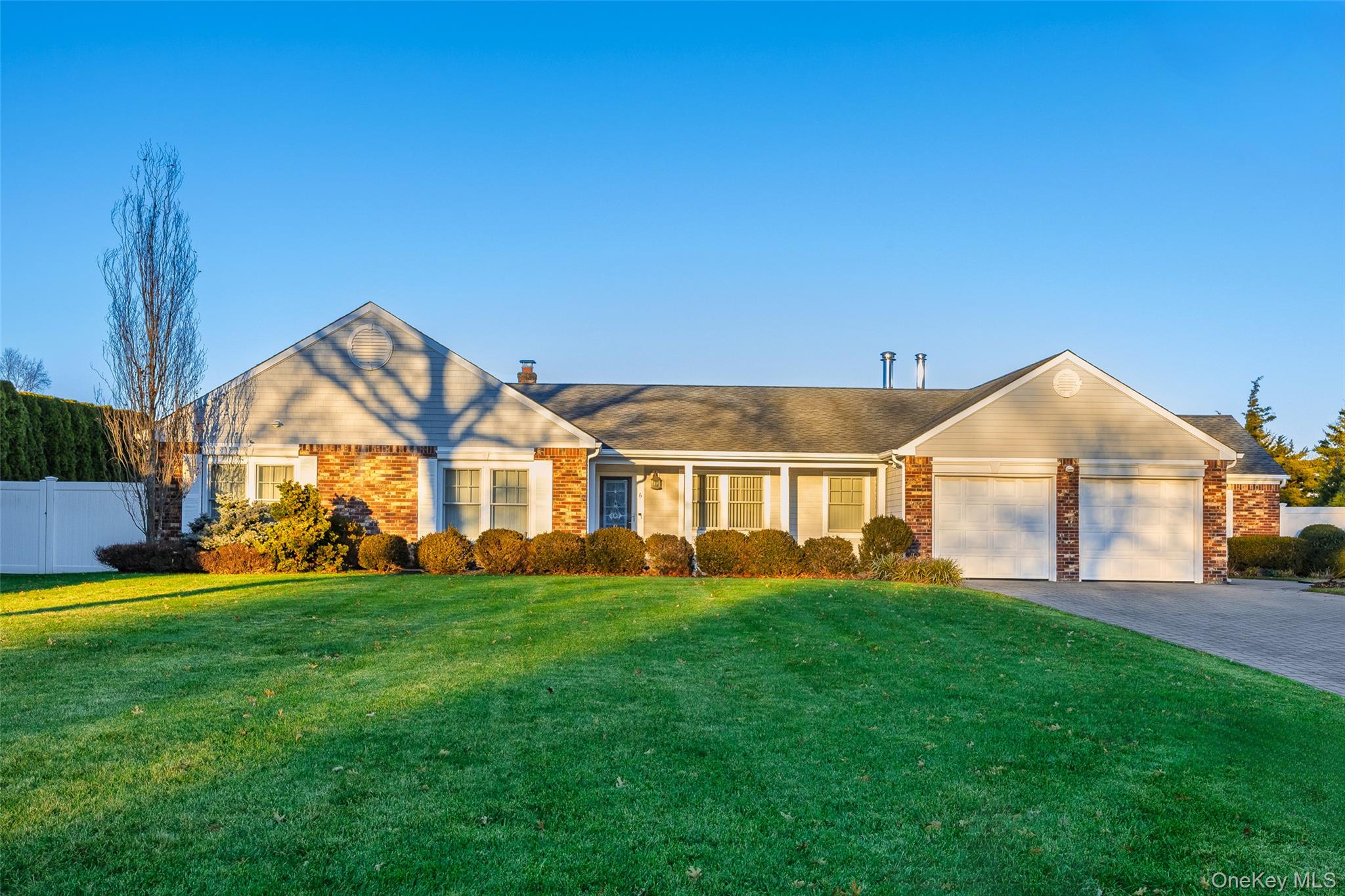 View of front of home with decorative driveway, brick siding, a garage, and a chimney