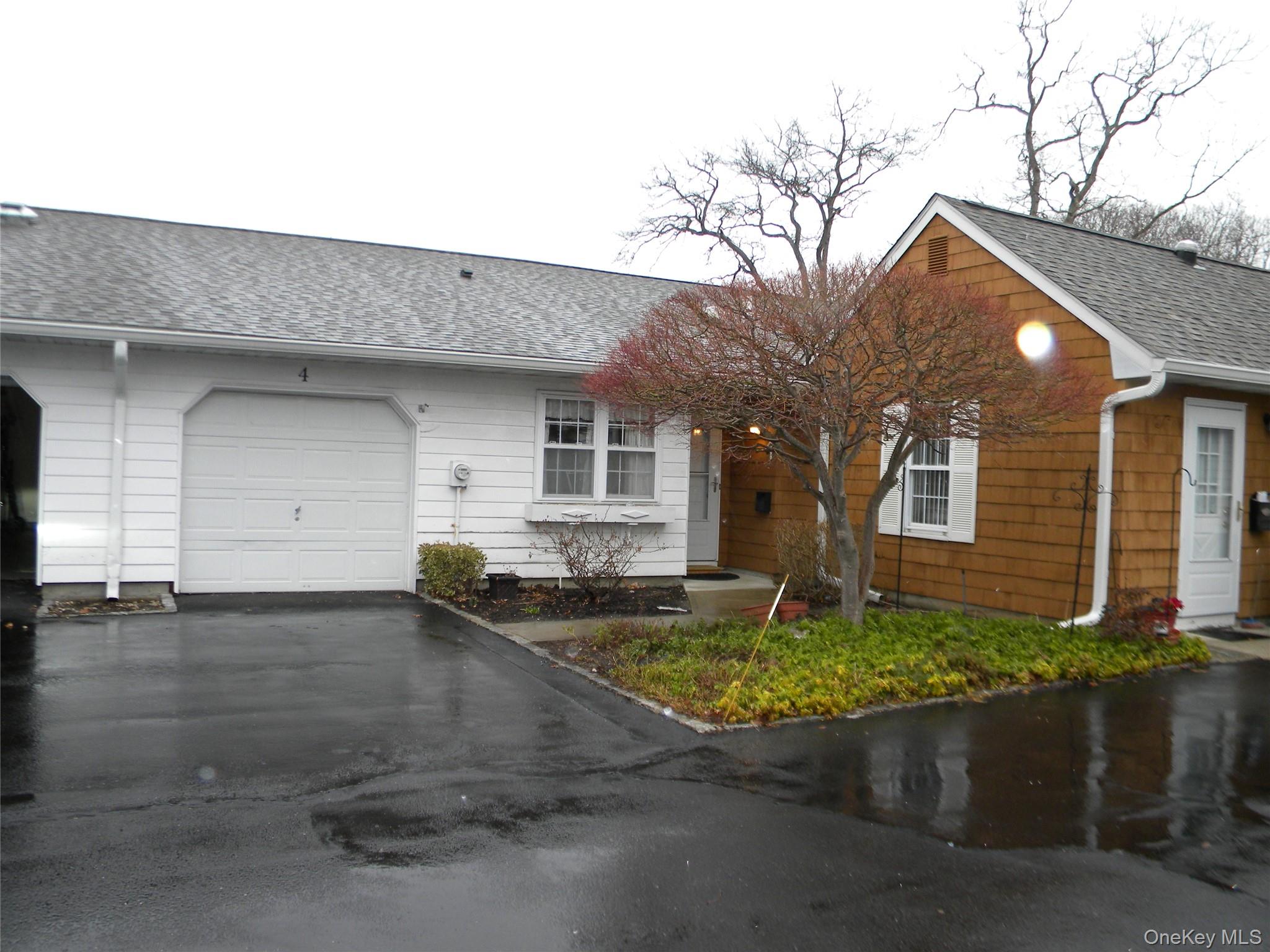 Ranch-style unit with roof with shingles, asphalt driveway, and a garage