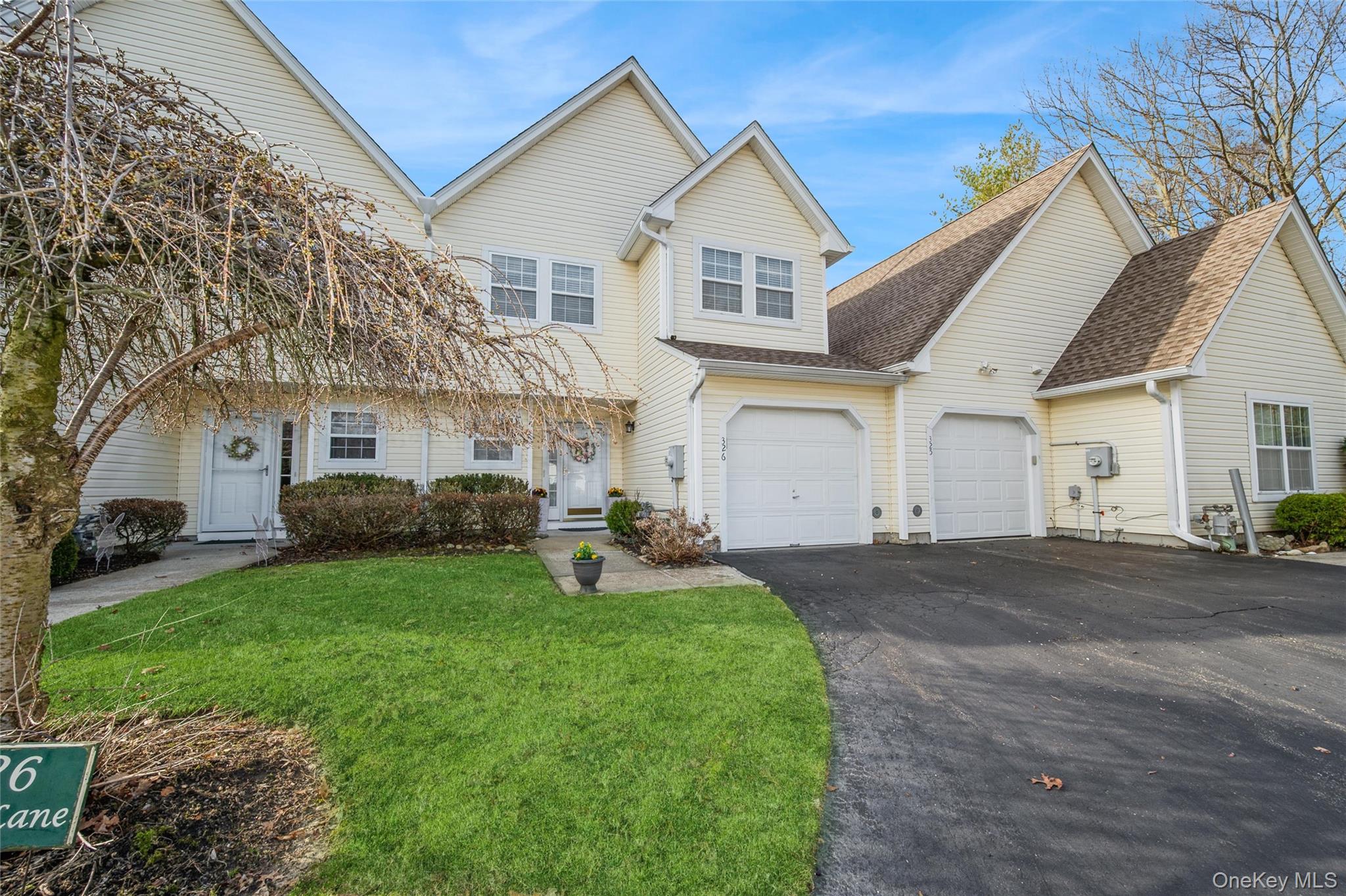 Traditional-style condo featuring asphalt driveway, a shingled roof, and a private front walkway and entrance