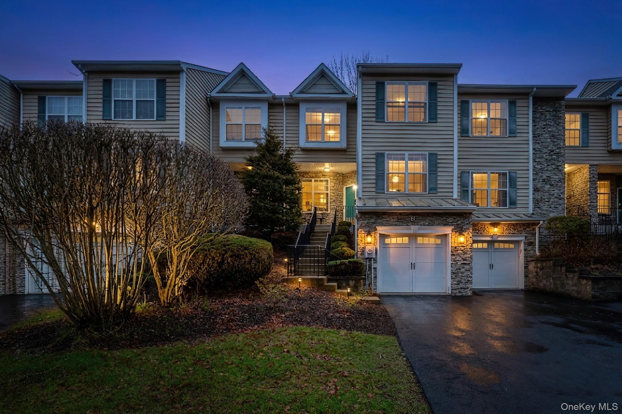 Traditional-style home featuring stone siding, asphalt driveway, and a garage