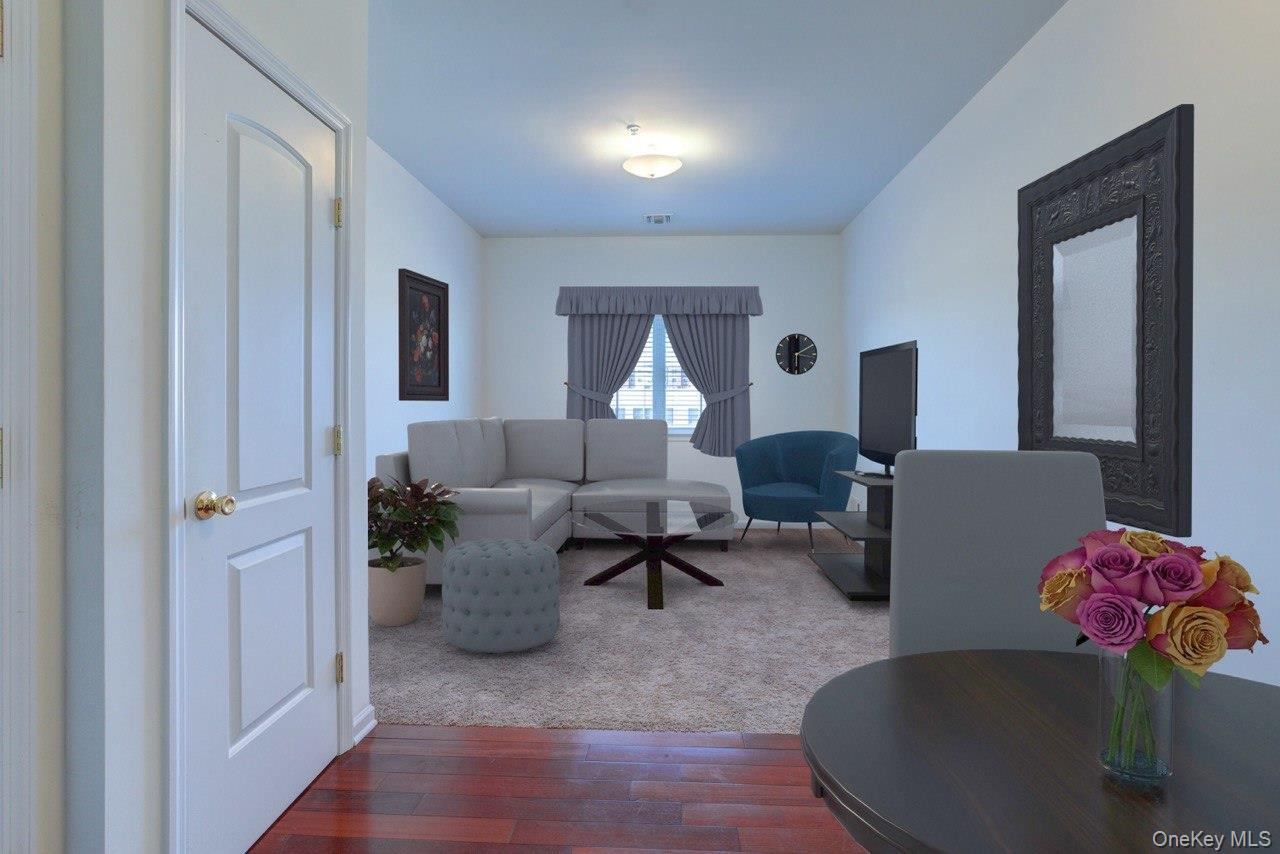 Open-concept living space featuring wood-finish flooring, white walls, and a recessed window