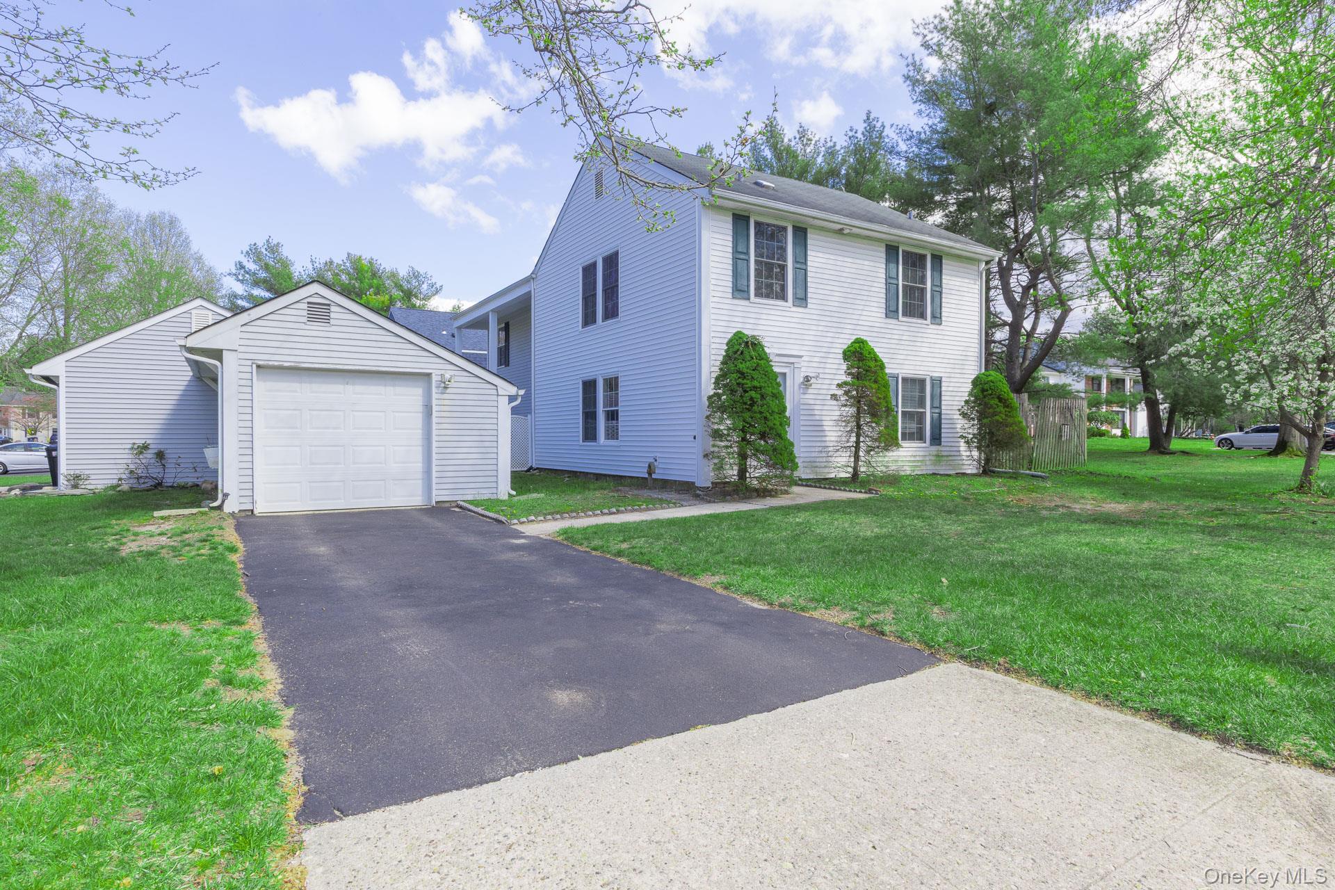 Two-story residence with white siding, window shutters, and a front yard with trees