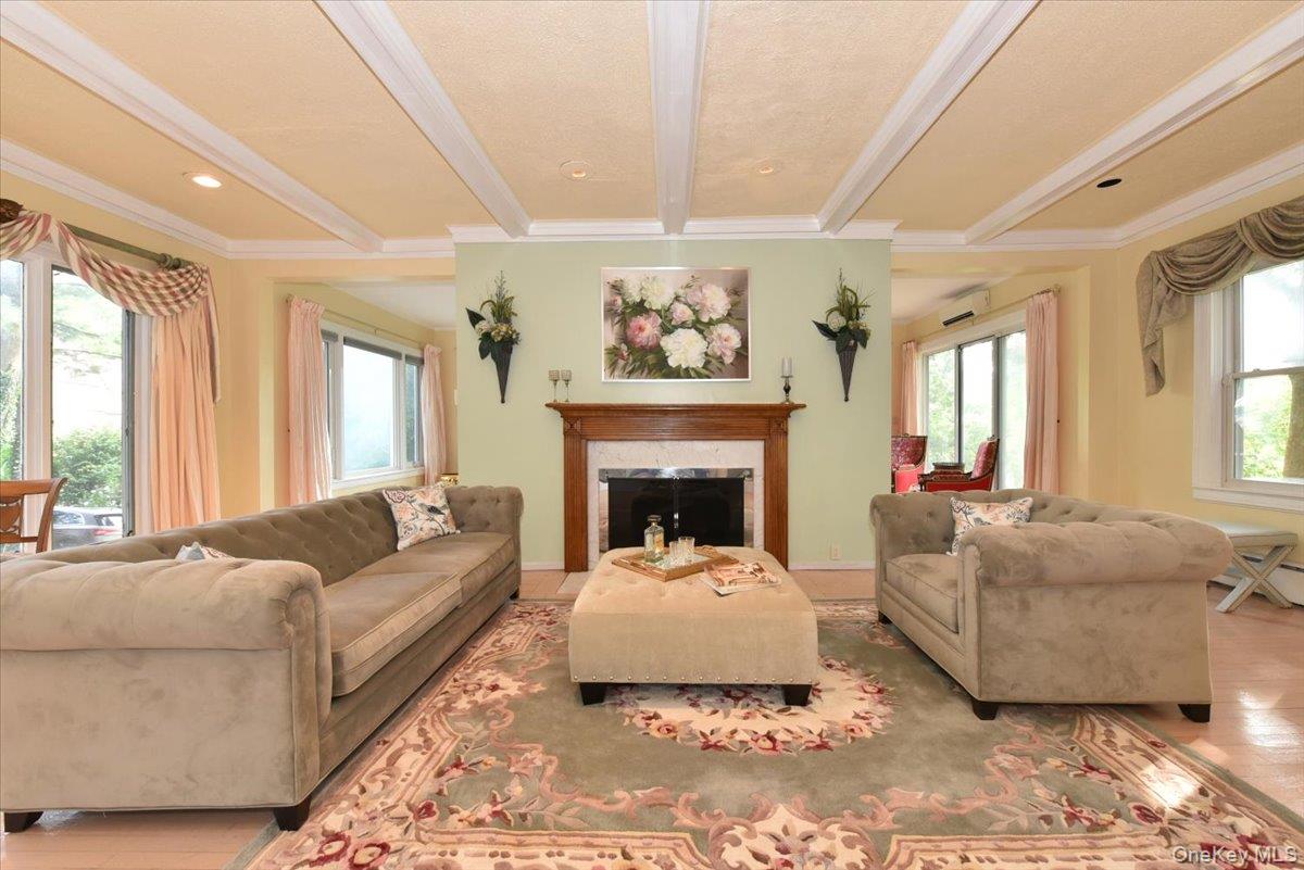 Living area with a high end fireplace, ornamental molding, beam ceiling, and wood finished floors